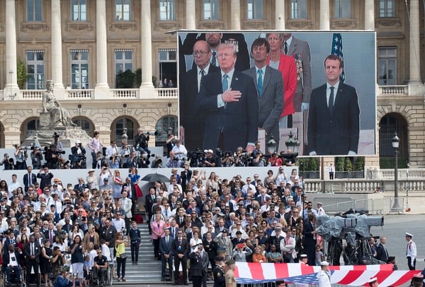 U.S. President Donald Trump and French President Emmanuel Macron are seen on a large screen as they stand during the American National Anthem during Bastille Day parade in Paris on July 14, 2017. (Carolyn Kaster/AP)