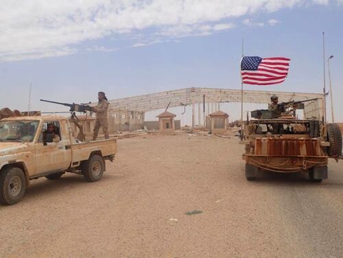 A U.S.-backed anti-government Syrian fighter mans a heavy automatic machine gun, left, next to an American soldier as they take their positions at Tanf, a border crossing between Syria and Iraq.